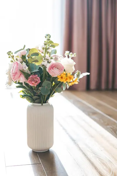 ランクルス 黄色の花束は白いリブベッドの花瓶を飾り ピンクのカーテンは柔らかく魅惑的な背景を花の配置に提供します ロイヤリティフリーのストック写真