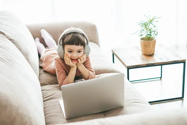Charming Year Old Girl Lying Sofa Wearing Headphones Watching Laptop Stock Image