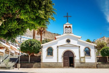Kutsal Ruh 'un küçük beyaz kilisesi üzerinde bir haç ve ön cephesinde bir saat, Los Gigantes, Tenerife' de yer almaktadır.