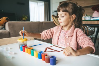 Küçük bir kızın resim masasında oturduğu yaratıcı bir an. Sanatsal sürece dalmış.