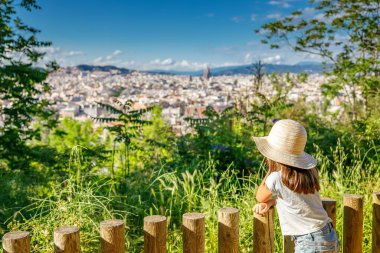 Barselona 'nın manzarası yükseldi. Hasır şapkalı genç bir kız şehrin binalarına ve ünlü sitelerine hayran kaldı. Şehir manzarasının güzelliğini gözler önüne serdi.