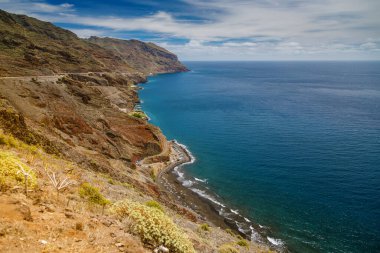 Tenerife 'deki Playa de las Gaviotas plajının havadan görünüşü, karanlık kumlar, kayalık uçurumlar ve denize uzanan dolambaçlı bir yol, seyahat içeriği için ideal.