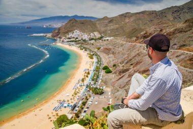 Tenerife 'deki Las Teresitas plajına bakan turist manzarası. Altında altın kumlar, palmiye ağaçları ve turkuaz suları var.