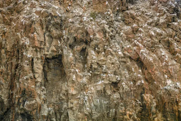 Karmaşık kaya oluşumları, açık bir günde doğal ışık tarafından vurgulanan çeşitli dokular ve renkler gösterir. Yüzey, çarpıcı manzaraya katkıda bulunan yıpranma şekillerini ortaya çıkarıyor..