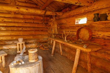 El yapımı aletler, kil çömlek ve doğal ışıkla aydınlatılan geleneksel mobilyaların bulunduğu kırsal ahşap kulübenin içi.