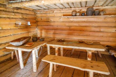 İçi ahşap ahşap kabin yemek masaları, ahşap banklar, kil kaplar, kuru otlar ve sıcak doğal ışık tanecikleriyle dolu.