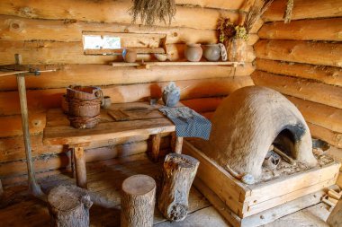 Kil fırını, ahşap masa, seramik kaplar, bitki demetleri ve rahat el yapımı atmosferi olan ahşap bir kulübe.