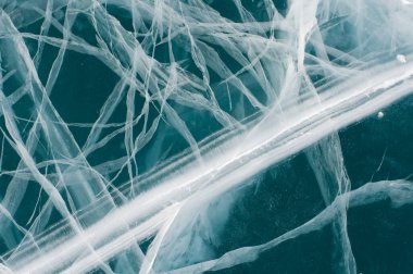 Fotoğrafta donmuş buz ve karmaşık çatlaklar görülüyor. Buz koyu mavi renktedir ve çatlakların beyaz çizgileri karmaşık ağ benzeri bir ağ oluşturur.. 