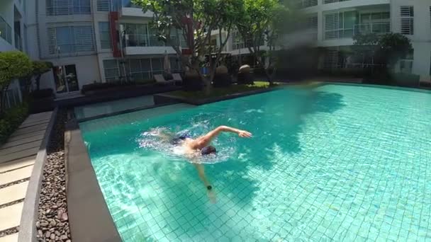 男は休暇中にプールで泳いでいる スローモーションビデオ 高品質のフルHd映像 — ストック動画