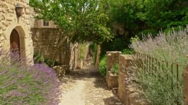 Lavantalı ve taştan evlerle dolu gölgeli bir cadde. Fransa 'nın antik şehri Lacoste, Provence' de. Fransa 'nın güneyindeki bir komün ve ortaçağ köyü olan Lacoste caddesinde yürüyorum. 4K, UHD titreşim