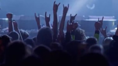 Rock konserindeki hayranlar. Sahne ışıklarında el çırpan insanlar. Bir konser ya da festival partisinde dans eden tanınmamış hayranlar. Parlak sahne ışıkları önünde konser kalabalığının siluetleri
