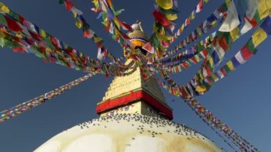 Boudhanath stupa, Katmandu, Nepal 'de. Kamera, Budist bayrakları arasında sallanıyor, güvercinler Boudhanath Pagoda kubbesinde oturuyor. UHD, 4K titreşimli çekim, yavaş çekim