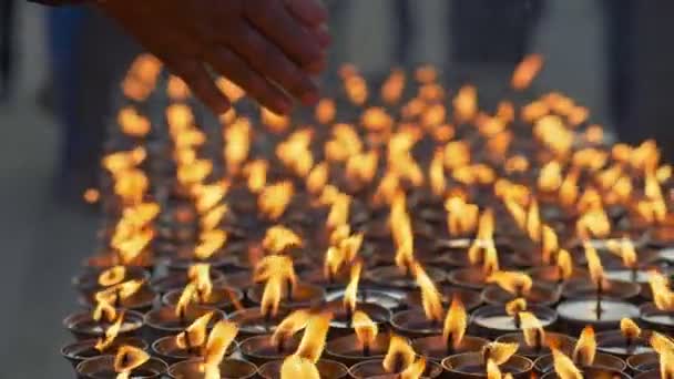 男は手をろうそくの上に暖めて祈る 仏教徒の仏教遺跡での祈りと燃えるろうそくの手 ネパールのカトマンズ スローモーションショット — ストック動画
