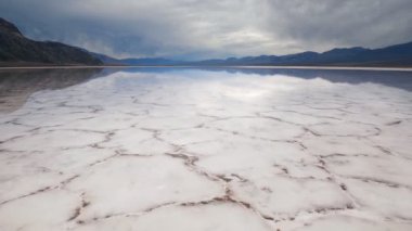Badwater Havzası, Ölüm Vadisi Ulusal Parkı 'nda tuz tabakası oluşumlarının ayna yüzeyinde yürüyor. Kaliforniya, ABD