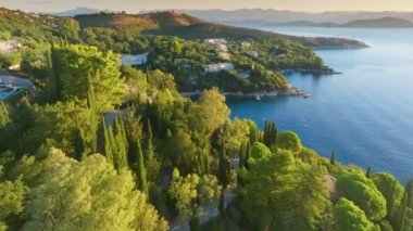 Gorgeous mediterranean landscape of Corfu island, Greece. Flying over lush green vegetation, villas and sea bays on Corfu island. Tourism landmark romantic honeymoon travel destination. Aerial shot