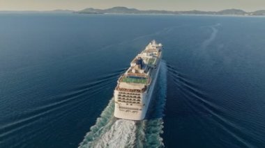 Flying over cruise ship in the sea. Huge cruise ship with football field and swimming pools approaches the shores of the island of Corfu, Greece. Aerial shot, 4K 2