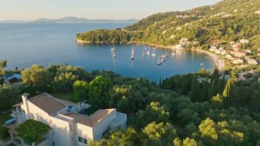 Korfu adasındaki yemyeşil bitki örtüsünün, villaların ve deniz koyunun üzerinde uçuyorlar. Yunanistan 'ın Korfu adasının muhteşem Akdeniz manzarası. Turizm tarihi bir balayı gezisi.
