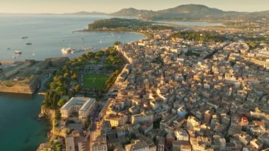 Flying over buildings, park and sea in Kerkyra, Corfu island. Aerial morning shot of Kerkyra, capital of Corfu island, Greece 2