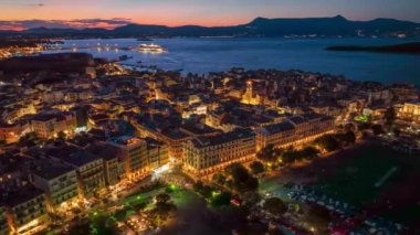 Old town with illumination against background of red sunset sky in Kerkyra, Corfu island. Evening aerial sunset view of Kerkyra, capital of Corfu island, Greece. 4K HDR shot 2