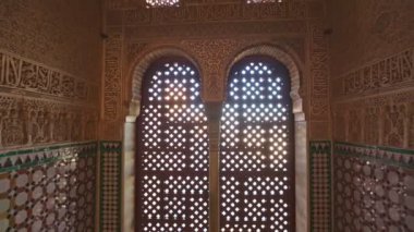 Kamera, Moorish süslemeleri ile duvarlar arasındaki pencerenin kemerlerine doğru hareket eder. Granada, Alhambra Sarayı 'nda muhteşem bir bozkır iç mekanı. Gimbal shot, 4K