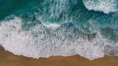 Deniz ya da okyanus sörf dalgası. Haddeleme ve bir kum plajı üzerinde geliyor köpüklü okyanus dalgaları. Hava yukarıdan aşağı atış, 4k