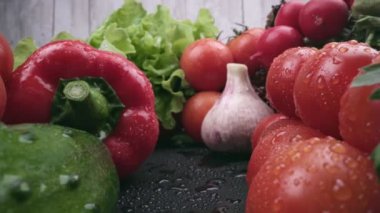 Taze organik ıslak sebzelerin Macro kaygan çekimi. Sağlıklı yaz sebzeleri hasadı. Domates ve salatalık, kırmızı biber, sarımsak, turp, maydanoz ve marul.