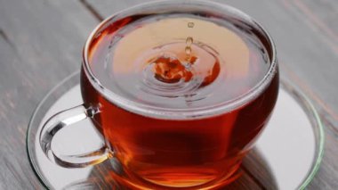 Kokulu siyah çay damlaları çay ile şeffaf fincana düşer. Yavaş çekim çay sıçraması.