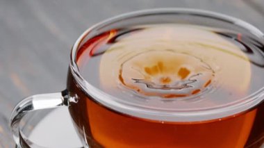 Bir fincan sıcak çaya siyah çay serpintisi yakın çekim. Bardağa çay dolduruyorum. Yavaş çekim