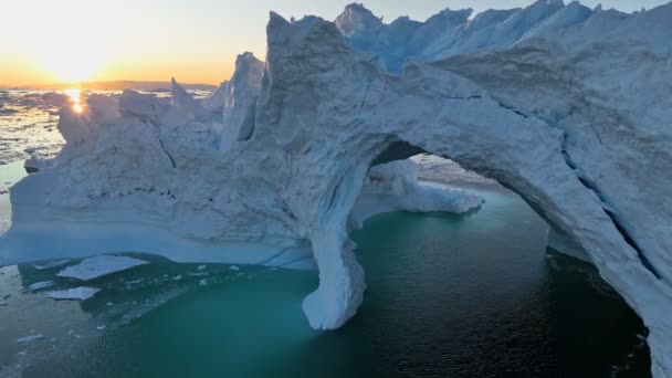 太陽を設定する空中ビューは氷山の先端を突破します 日没の氷の洞窟でアイスバーグ 氷河の融解 地球温暖化 北極圏の自然景観 — ストック動画