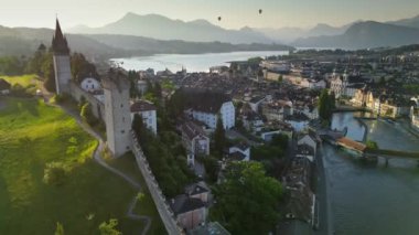 Lucerne 'in eski kasabası ve Reuss Nehri' nin sabah manzarası. İsviçre, Luzern 'deki gözetleme kulelerinin ve şehir duvarlarının manzarası. Arkaplanda İsviçre Alpleri
