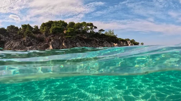 希腊Halkidiki市Sitonia的水晶清澈海水 从空气和水的边界与穹顶射击 沙质海滩底部和有树木岩石的半水下慢镜头2 免版税图库照片