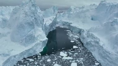 Okyanusta karla kaplı dev buz dağları. Ilulissat, Grönland yakınlarındaki dev buzdağının yanında uçuyor. Hava kutbu doğa manzarası, küresel ısınma ve iklim değişikliği kavramı