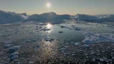 Buzdağlarının üzerinde batan güneşin havadan görünüşü. Ilulissat, Grönland. Buzulların erimesi, küresel ısınma, kutup doğası.