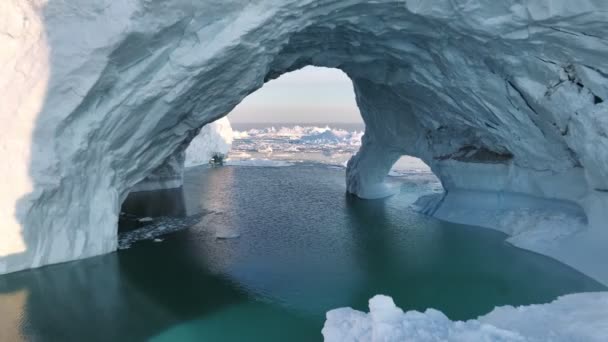 氷の洞窟の中を飛んでいる 氷の洞窟で氷山が溶け出した氷山 グリーンランドのイルリサット近くのディスコ湾の氷河の融解から氷山 航空ショット 気候変動コンセプト — ストック動画