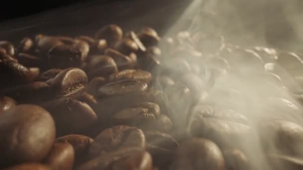 暗い背景で喫煙したコーヒー豆を焙煎します 煙は新鮮なコーヒーの種から来る ロースト中にコーヒー豆をスライダーショット スーパーマクロショット — ストック動画