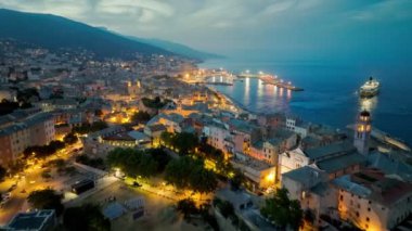 Bastia limanı ve eski kasabanın hava manzarası, feribot limandan ayrılıyor, Akdeniz, Korsika, Fransa. Akşamları Bastia 'nın üzerinde uçuyor Şehir ışıklarıyla, Korsika adası