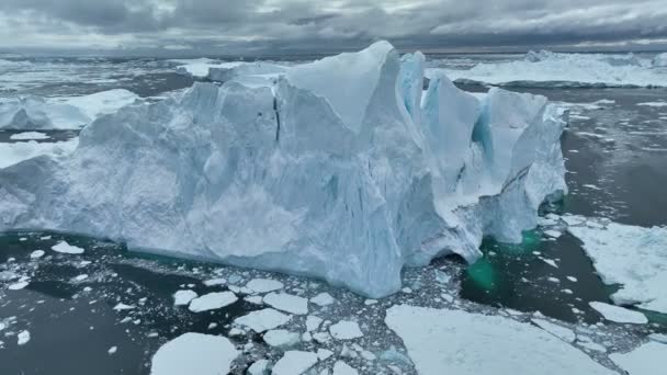 グリーンランドのイルリサット近くの巨大な氷山の近くで飛んでいる 氷山の断片が分裂して水に落ちる 地球温暖化と気候変動のコンセプト — ストック動画
