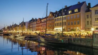 Kopenhag, Danimarka 4K HDR 'da. Nyhavn Kanalı New Harbour 'un renkli evleri ve Kopenhag' da yelkenli tekneleri olan akşam çekimleri.