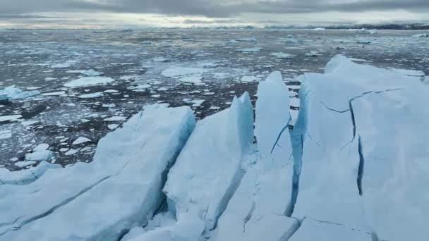 グリーンランドのイルリサット近くの巨大な分割氷山の近くで飛行 海で雪に覆われた氷山の巨大なブロック 地球温暖化と気候変動のコンセプト — ストック動画