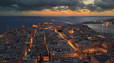 Gün doğarken Valletta 'nın eski kasabasında uçuyorum, Malta. Malta 'da şehrin ışıklarıyla Valletta' nın havadan sabah görüntüsü. UHD, 4K. 