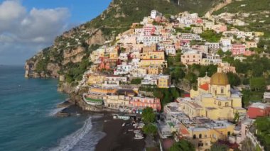Amalfi sahilinin ünlü turistik beldesi, Positano. Renkli evlerin, kilisenin ve plajların üzerinde turkuaz suyla uçuyor. Positano köyü, İtalya. UHD, 4K