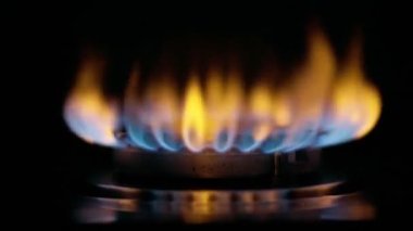 Yavaş çekim UHD gaz sobası ateşlemesi. Gaz ocağı siyah arka planda yanıyor. Doğal gaz konsepti. Yüksek kalite 4k görüntü
