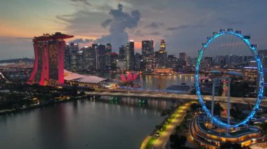 Singapur şehir ışıklarının günbatımı arkaplanlı akşam çekimleri. Singapur 'daki Marina Körfezi üzerinde uçuyor. Yüksek kalite 4k görüntü