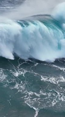 Güçlü dalgaların düşüşünün yavaş çekim görüntüsü. Deniz ya da okyanus büyük fırtınalı sörf köpüklü beyaz dokuya sahip berrak turkuaz su. Dikey Ekran