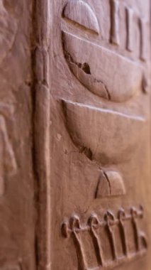 Hatshepsut tapınağındaki duvarda Mısır hiyerogliflerinin yakın çekimi. Eski Mısır hiyeroglifleri oyulmuş antik taş duvar. Sığ DOF, Dikey Ekran