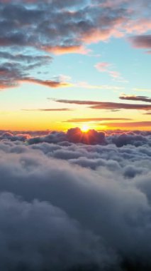 Güneş bulutların üzerinde sabahın erken saatlerinde bir bulutun arkasından çıkar. Sabah güneşiyle aydınlanan bulutların üzerinde uçuyor. Gökyüzünde destansı gün doğumu. Dikey Ekran