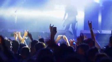 Rock gitaristi yaz müzik festivalinde sahne konserinde sahne alacak. İnsanlar rock konserinde dans edip ellerini kaldırıyorlar.