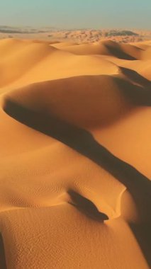 Rub al Khali - Boş Mahalle, Arap Yarımadası. Çölde kum tepelerinin üzerinde uçuyor. Kamera sağa doğru hareket ediyor. Havadan dikey çekim