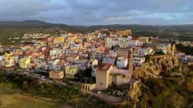 İtalya 'nın Sardunya adasındaki Castelsardo eski kasabasında uçuyorum. Castelsardo 'da günbatımında tepenin üstünde eski renkli evler ve şato 