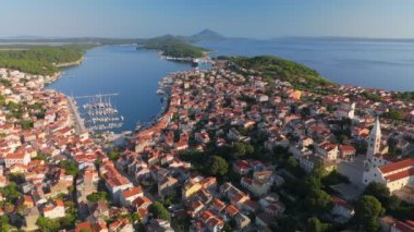Kutsal Bakire Meryem 'in Doğumu Kilisesi ve Hırvatistan' ın eski Mali Losinj kasabasının üzerinde uç. Losinj ve Cres adaları arka planda. Hava görüntüsü, UHD